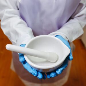 Close-up of a pharmacist holding white mortar and pestle in lab attire
