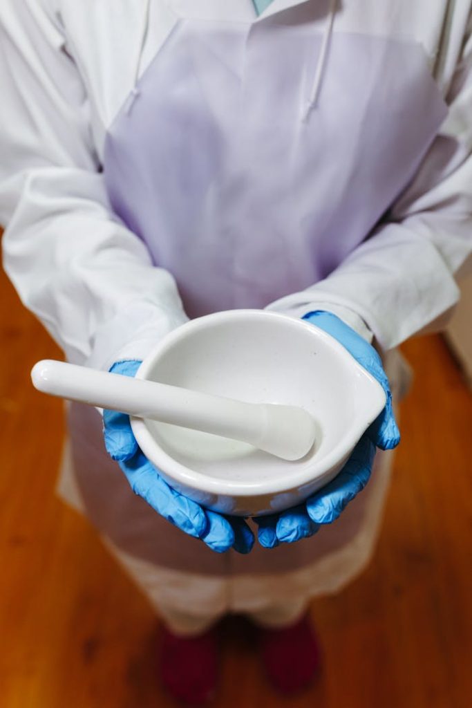 Close-up of a pharmacist holding white mortar and pestle in lab attire